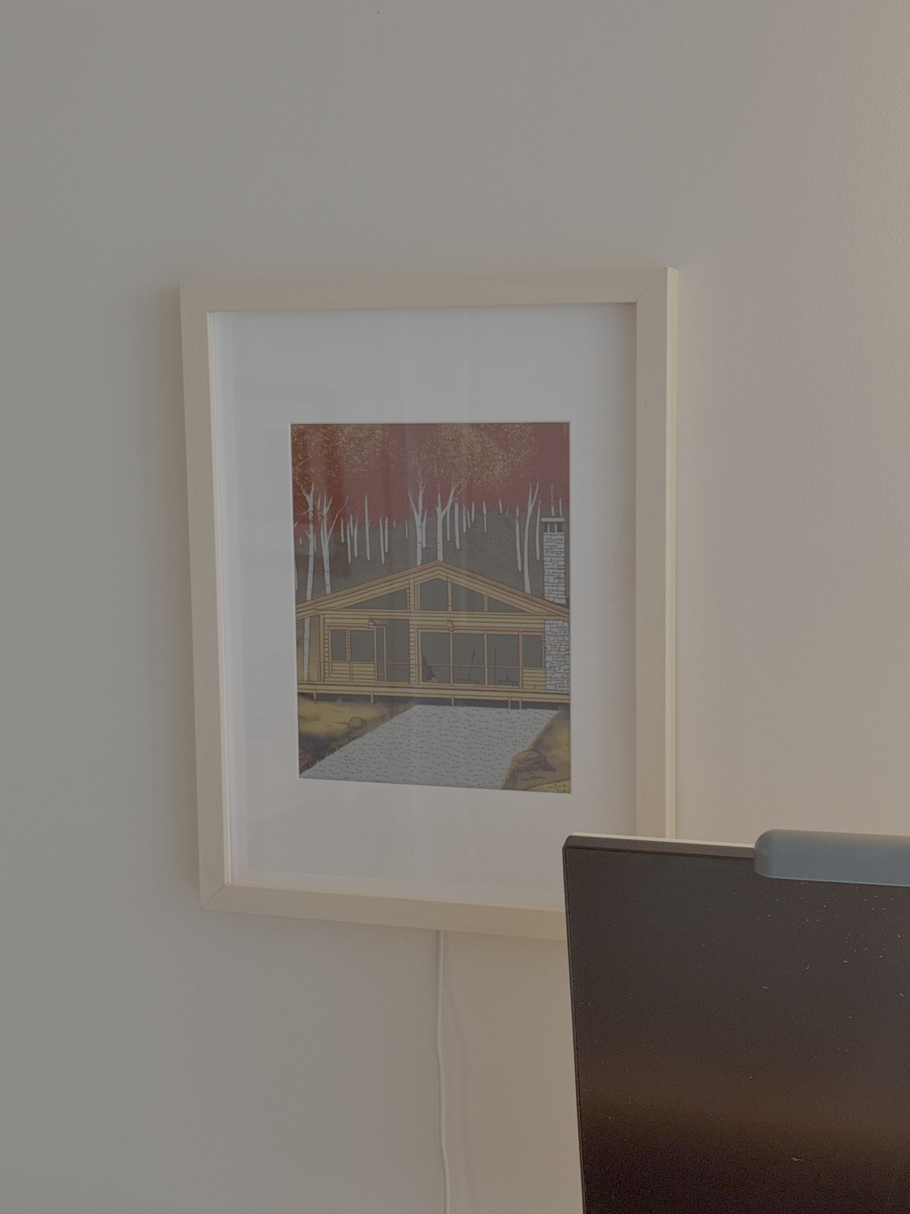 A photo of the e-ink frame mounted with a cabin print displayed